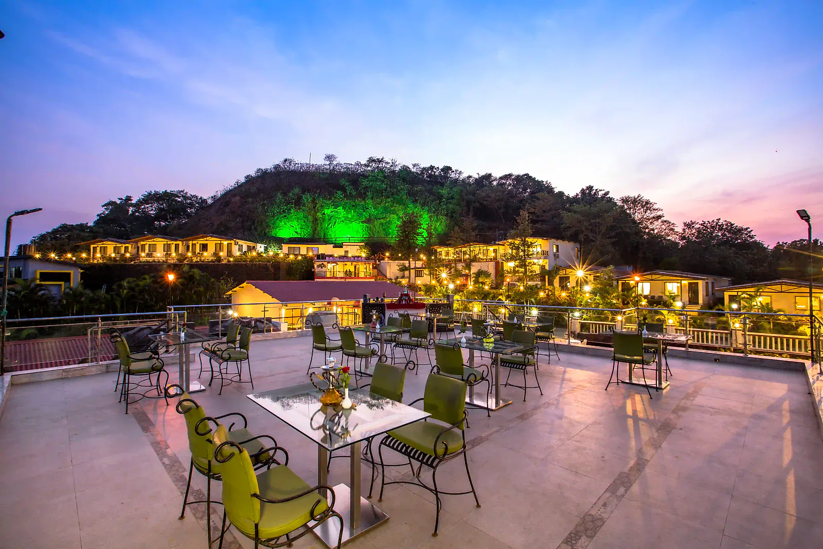 Open-air rooftop tables at dusk with the hills lit behind