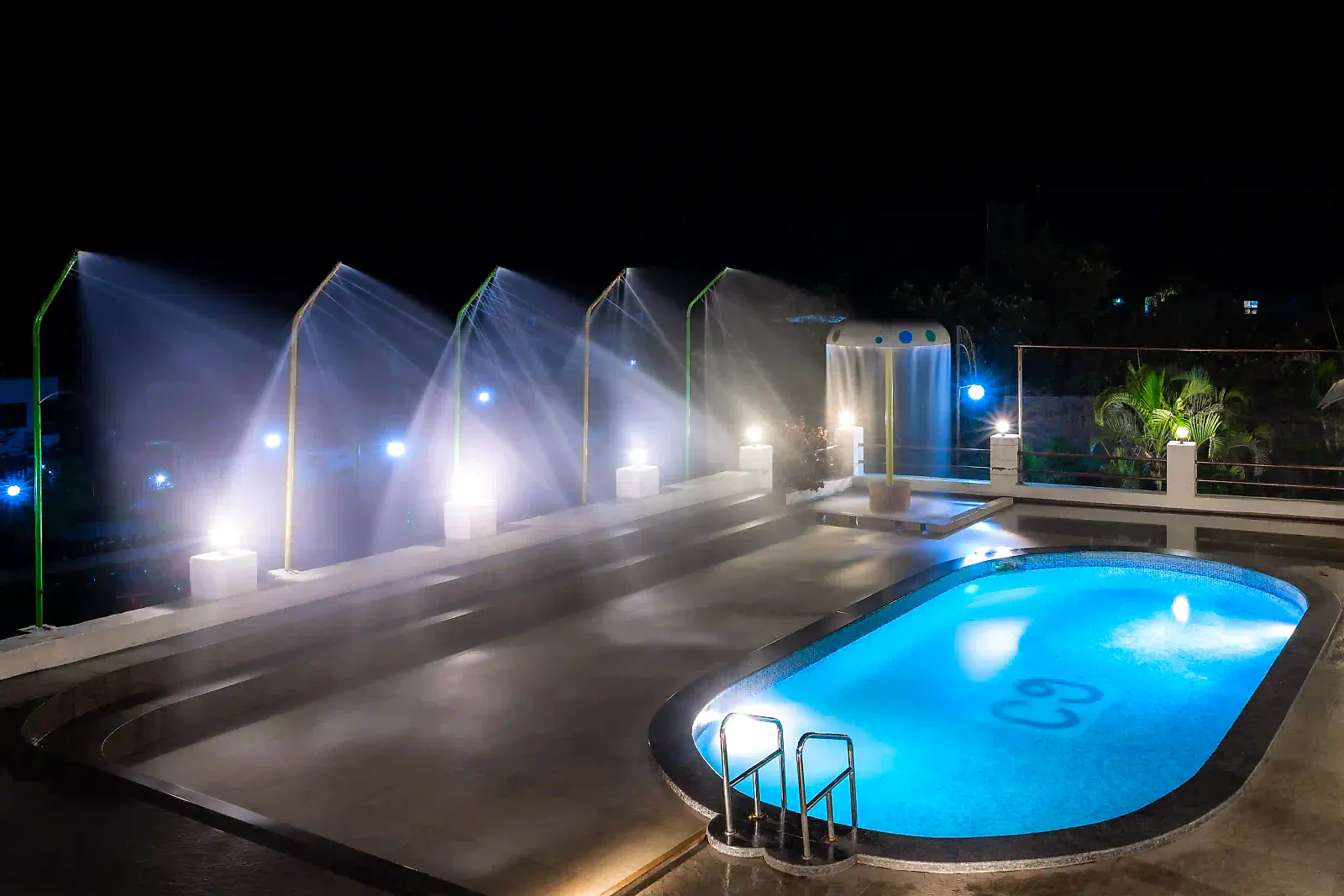 The pool lit up at night with rain-dance fountains