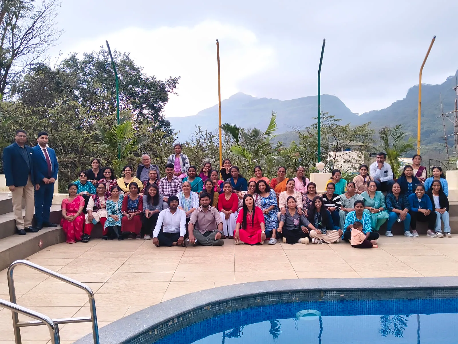 A corporate group gathered by the pool at Cloud 9 with the hills behind