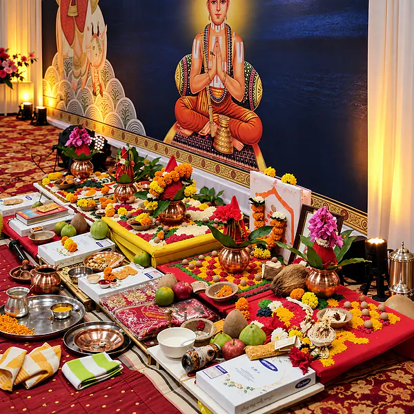 Pooja offerings of fruit, flowers and brass vessels arranged before a deity backdrop
